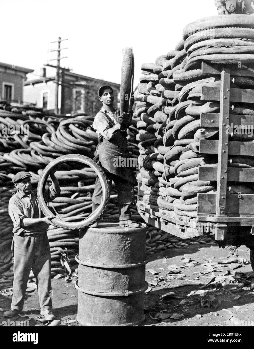 Cambridge, Massachusetts : 1925. La plus grande pile de pneus automobiles au monde est ici aux chantiers de caoutchouc de Feinberg à Cambridge, où chaque jour des milliers d'entre eux sont coupés et fondus vers le bas pour leur caoutchouc. L'entreprise est condamnée à l'annonce de Harvey Firestone qui a obtenu une énorme concession de caoutchouc au Libéria, qui finira par contrôler la moitié de l'offre mondiale, ce qui rend des entreprises comme celle-ci non rentables. Banque D'Images