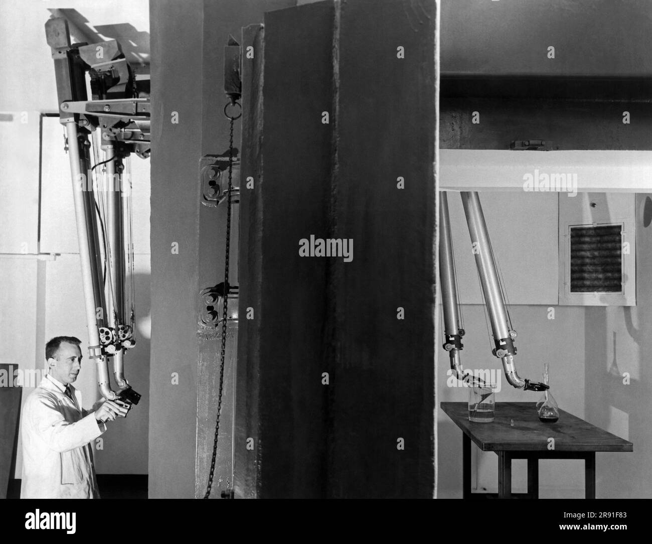 Chicago, Illinois, 1956 Dr. Leonard Reiffel, directeur de recherche à la Fondation de recherche Armor de l'Institut de technologie de l'Illinois, exécutant le manipulateur esclave derrière trois pieds épais fenêtres dans la cellule chaude du nouveau réacteur nucléaire. Banque D'Images