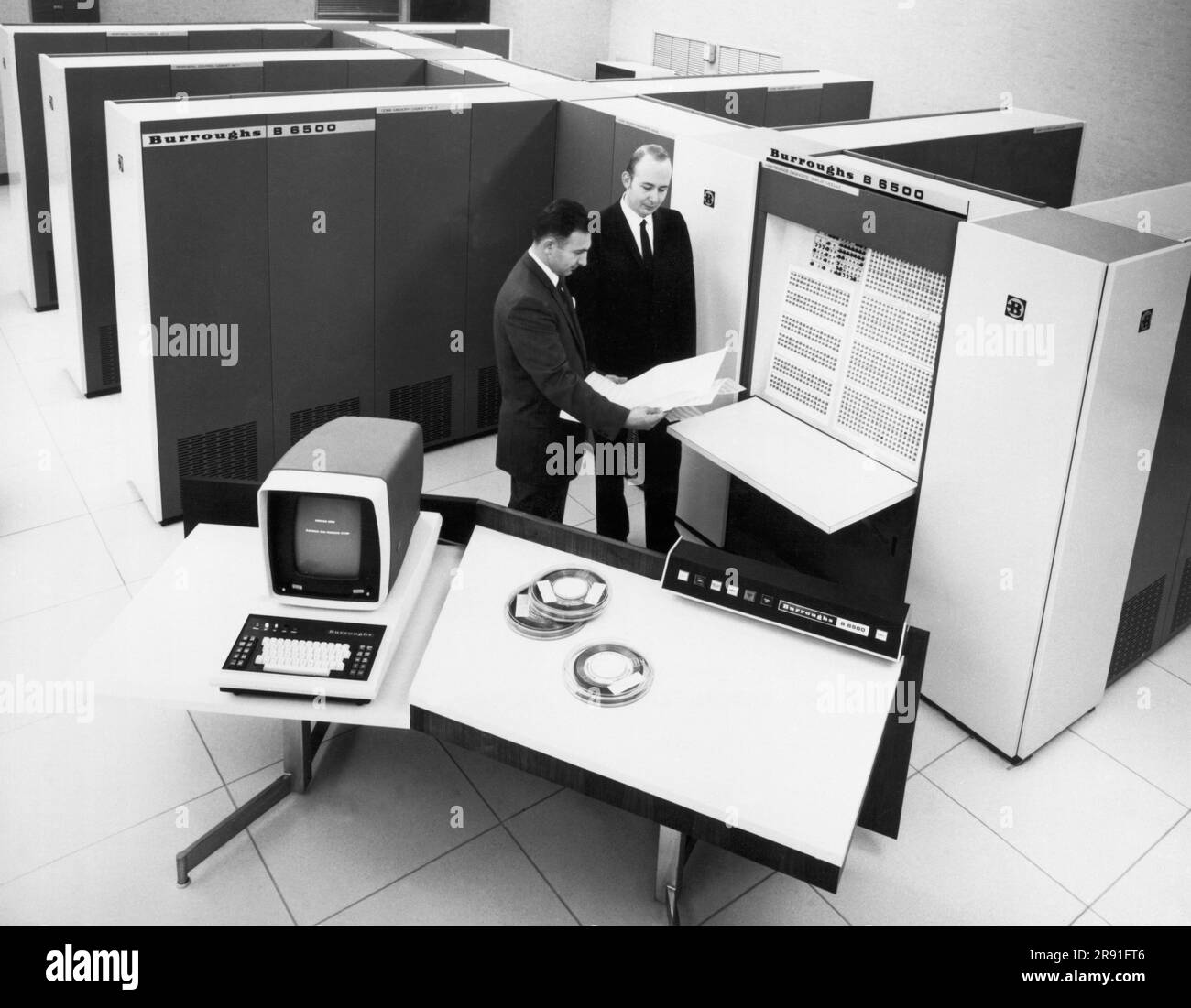 États-Unis : 1969 les spécialistes en systèmes informatiques de Burroughs Corporation examinent une impression du modèle d'affichage de diagnostic de maintenance du nouveau système informatique B6500. Banque D'Images