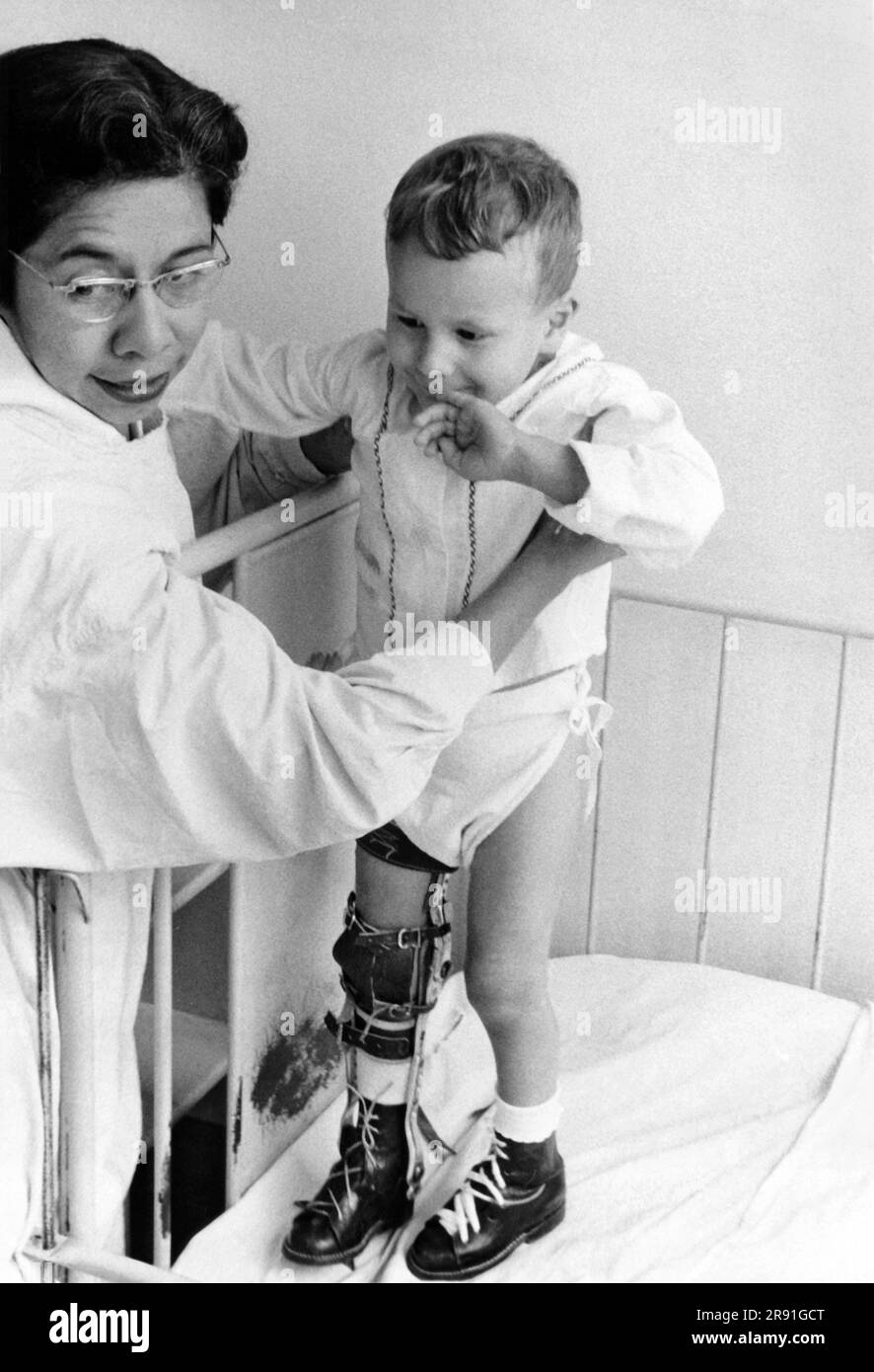 San José, Costa Rica: 1955 Un enfant du service de polio de l'hôpital San Juan de Dios assisté d'un travailleur de l'ONU Administration de l'assistance technique. Banque D'Images