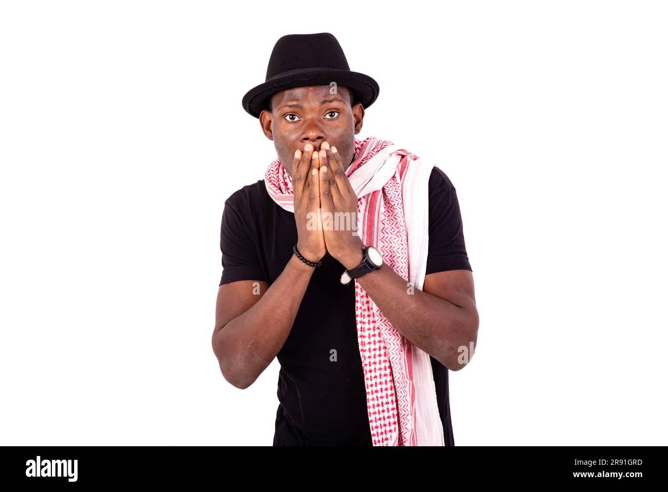 surpris jeune homme portant un chapeau et un foulard, couvrant la bouche avec ses mains. Banque D'Images