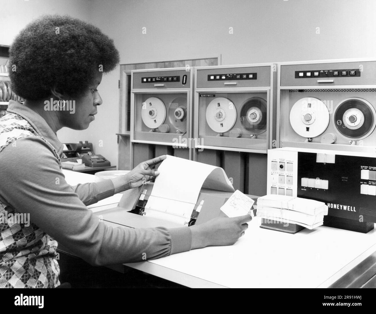 États-Unis : c. 1969 Une femme travaillant sur un ordinateur à lecteur de bande Honeywell. Banque D'Images