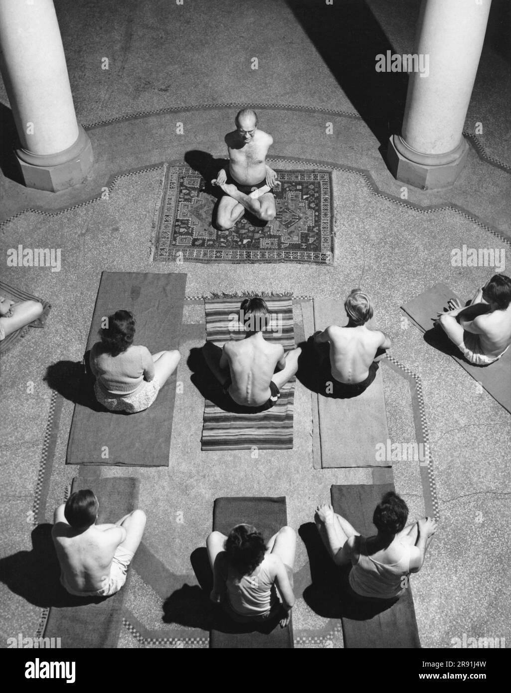 Etats-Unis: 2 décembre 1949 Un cours de yoga se tient dans un hall où les étudiants s'assoient attentivement sur leurs tapis comme le démontre Yogi Bittner en se nouant dans des nœuds. Banque D'Images