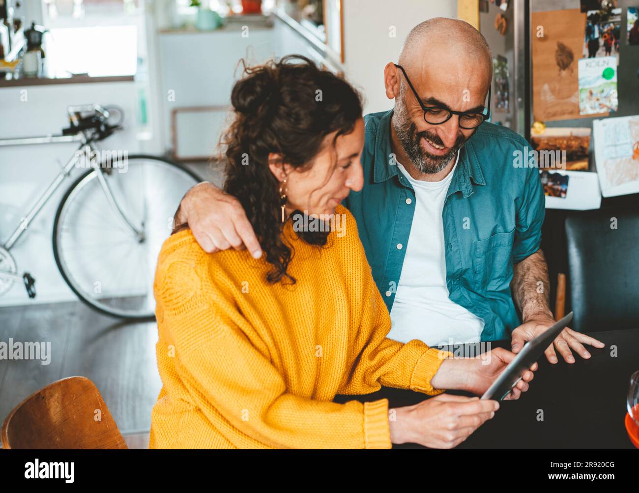 Homme avec le bras autour de la femme utilisant un Tablet PC à la maison Banque D'Images