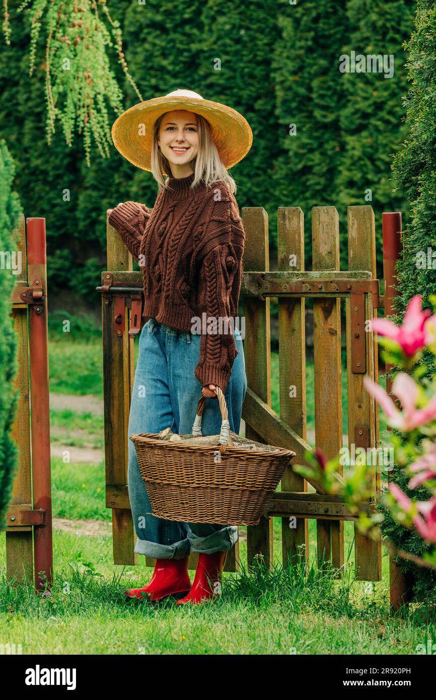 Femme souriante portant un panier de bois de chauffage dans le jardin Banque D'Images