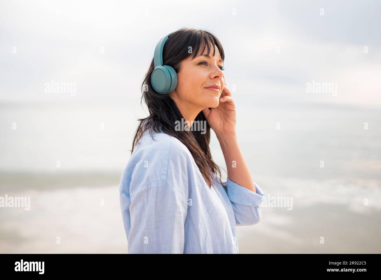 Femme réfléchie passant du temps libre à écouter de la musique à la plage Banque D'Images
