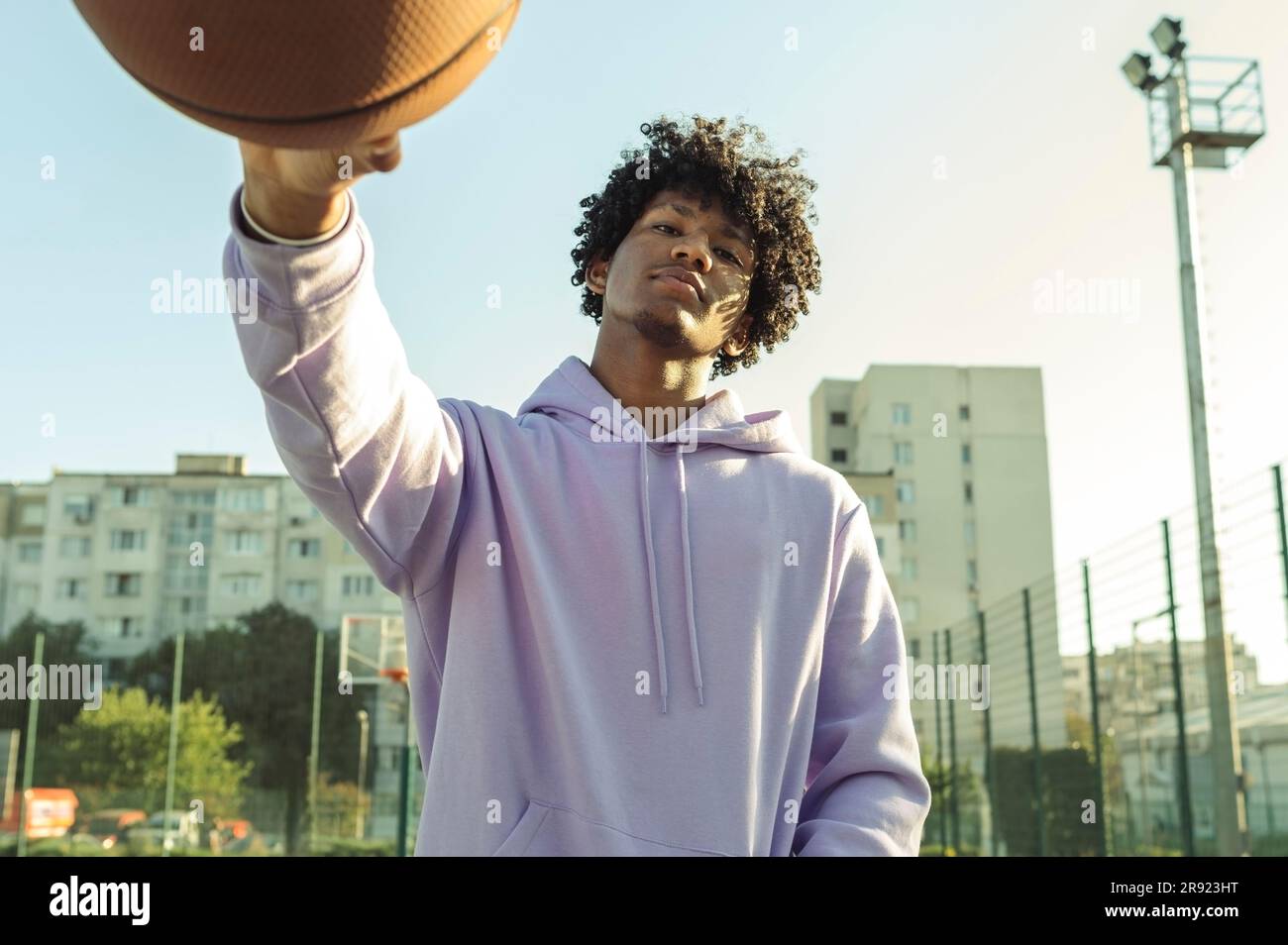 Athlète confiant portant un sweat à capuche violet tenant le basket-ball sur le terrain de sport Banque D'Images
