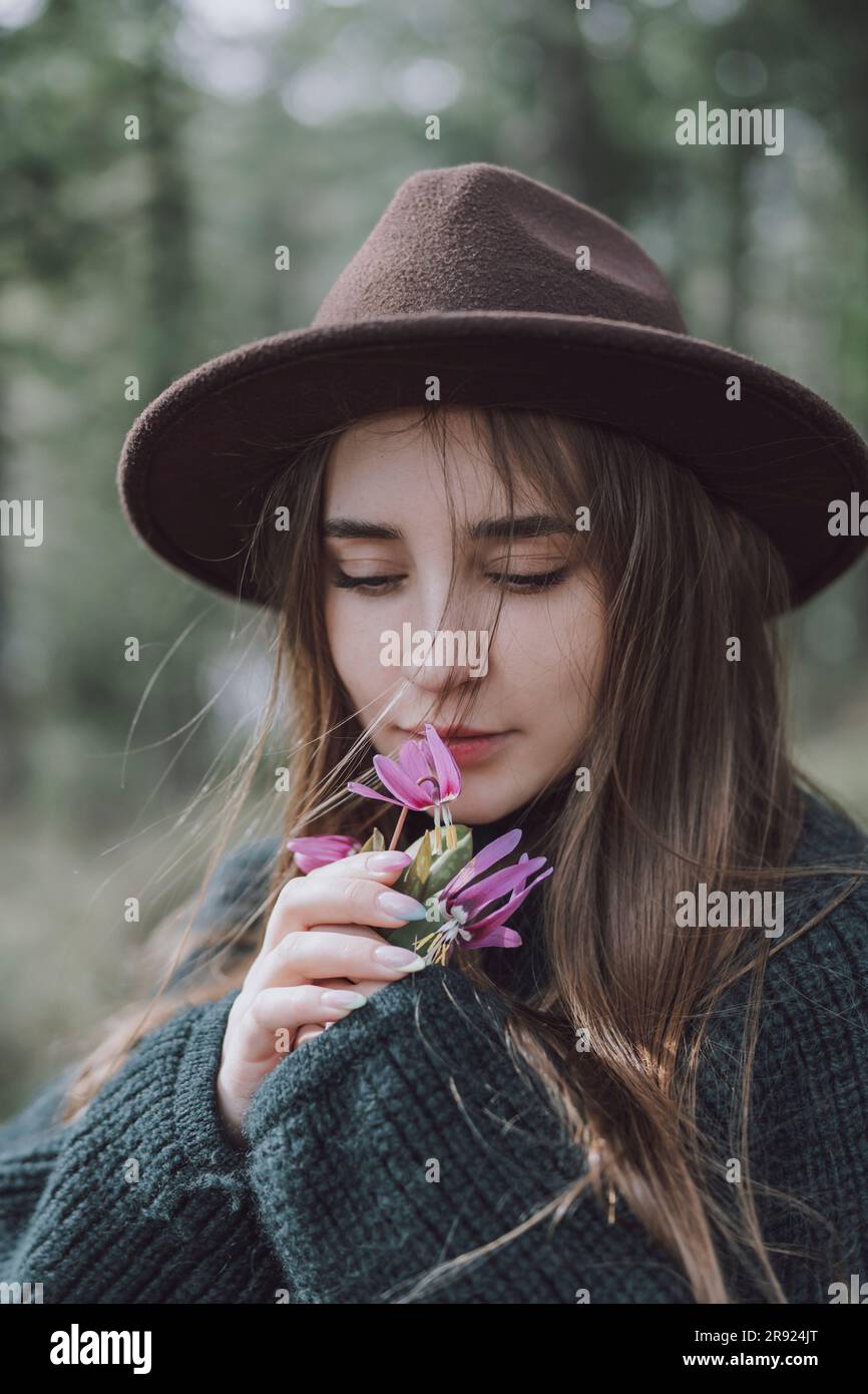 Belle jeune femme aux cheveux longs qui sentent des fleurs Banque D'Images