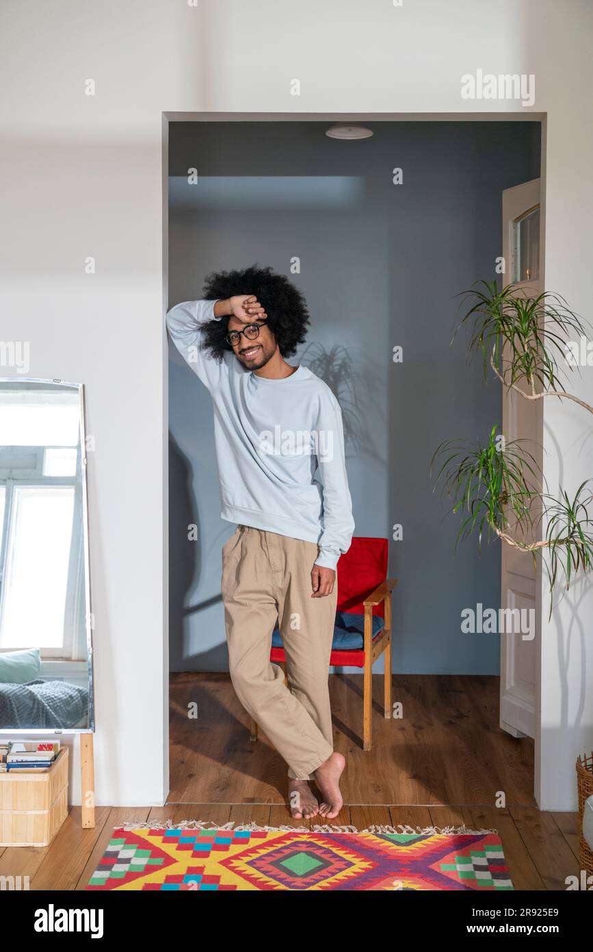 Homme souriant s'inclinant sur le mur à la maison Banque D'Images