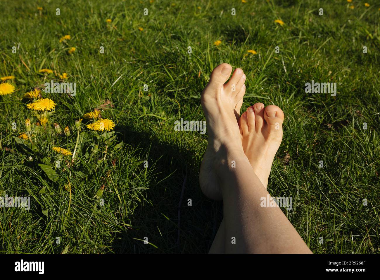 Femme avec les jambes croisées sur l'herbe à la journée ensoleillée Banque D'Images