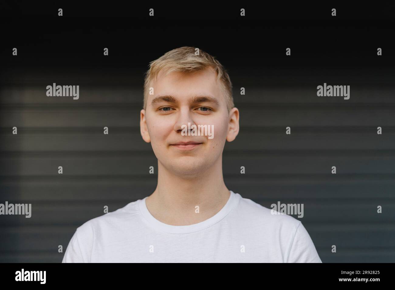 Jeune homme souriant devant l'obturateur fermé Banque D'Images