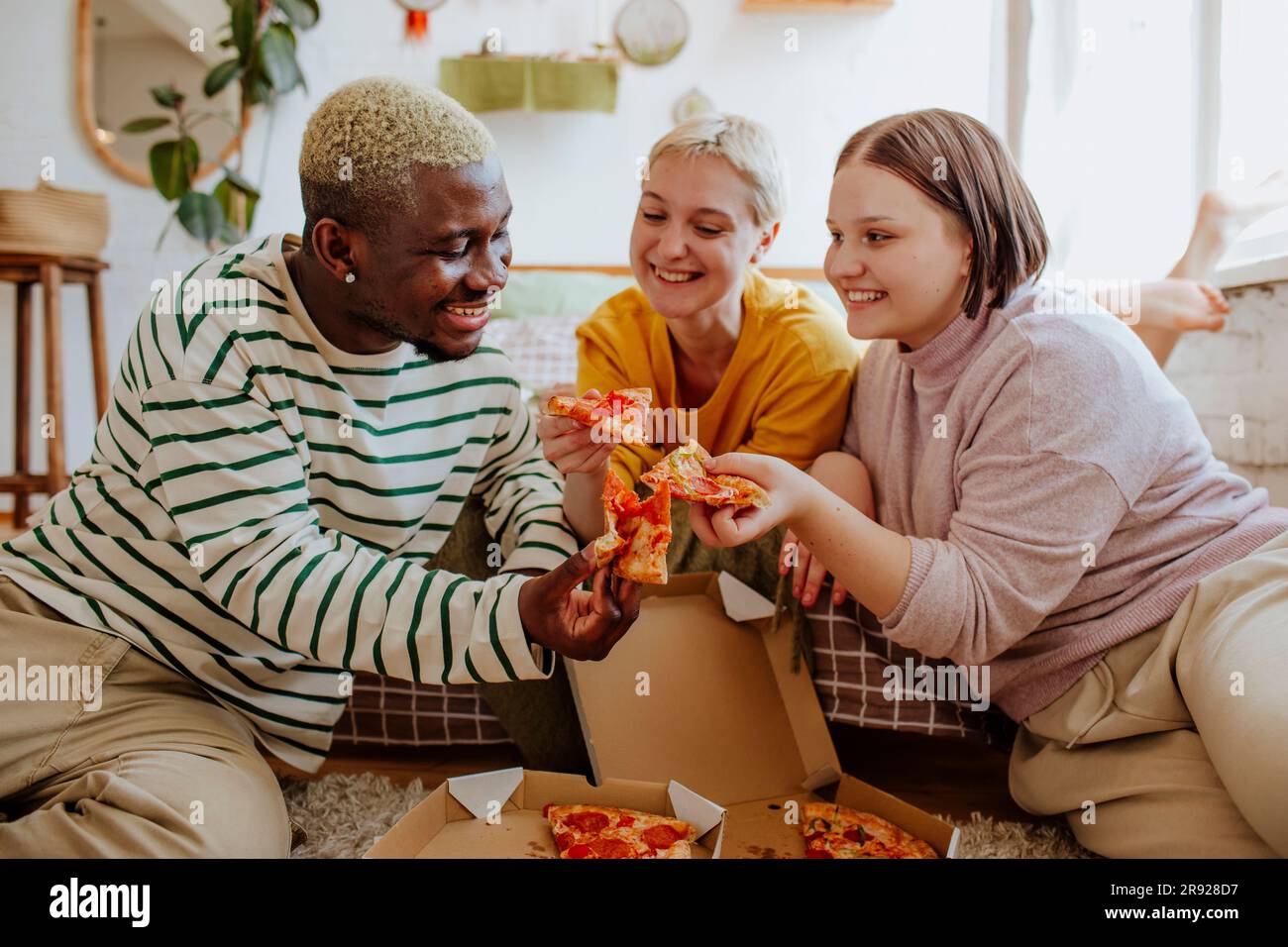 De jeunes amis heureux qui mangent de la pizza à la maison Banque D'Images