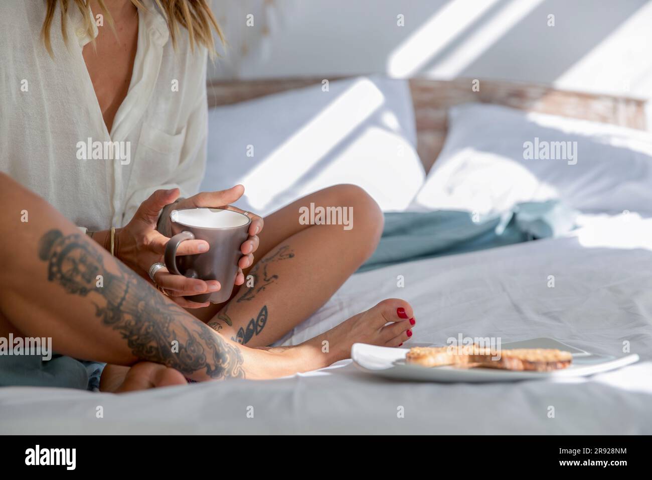 Femme assise au lit et prenant le petit déjeuner à la maison Banque D'Images