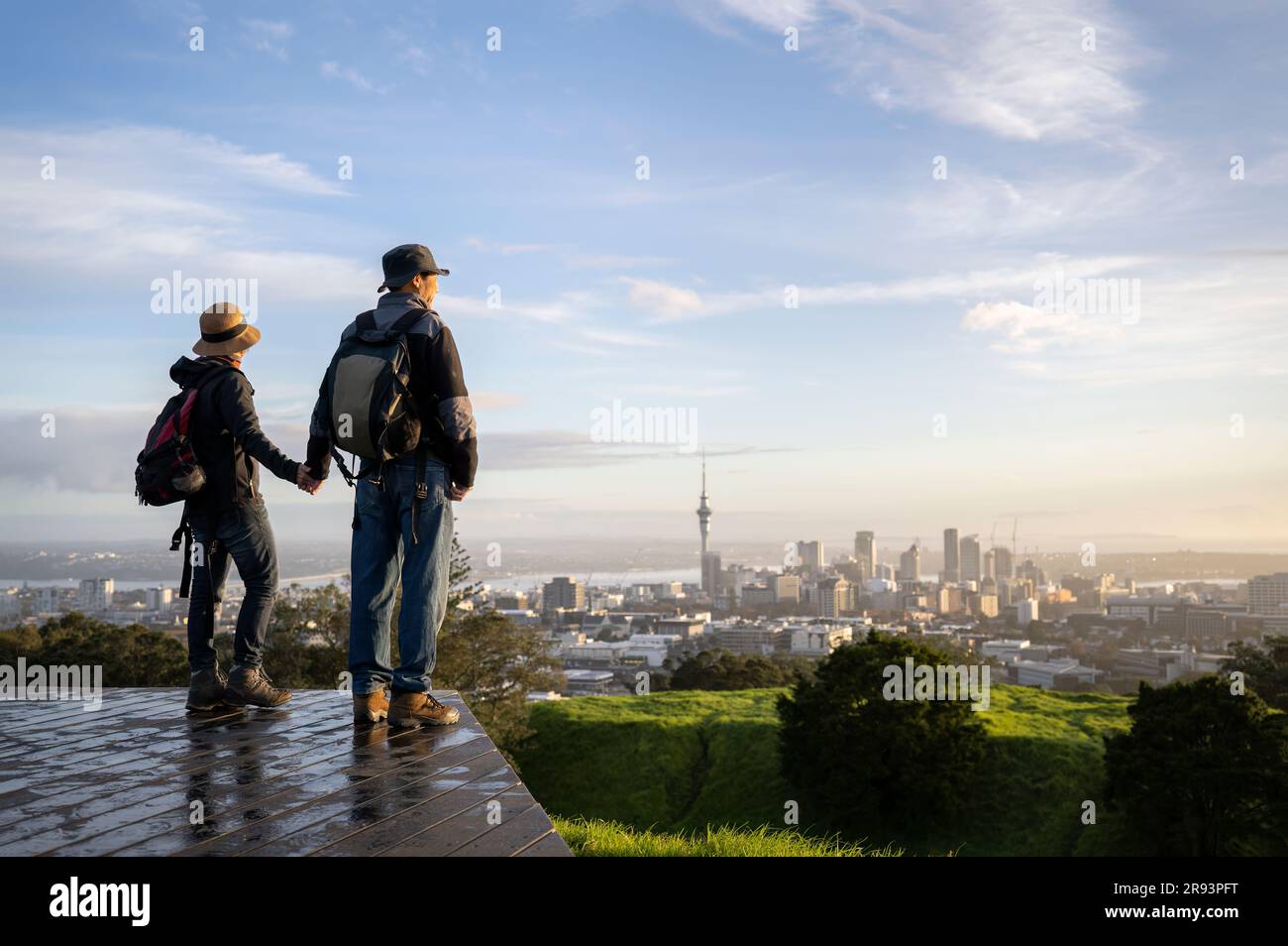 Couple debout au sommet du Mont Eden et regardant le lever du soleil sur la ville d'Auckland. Accent sélectif sur les personnes au premier plan. Banque D'Images