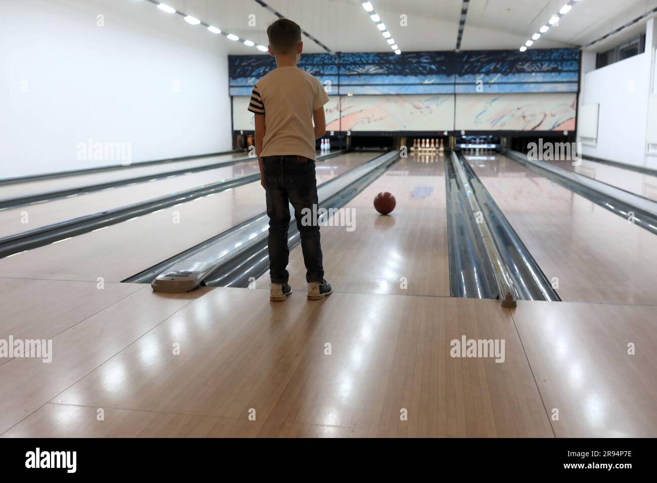 Les enfants regardent le ballon dans la piste de bowling Banque D'Images