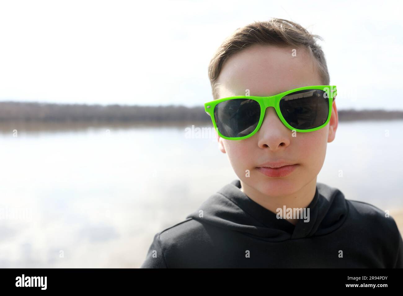 Portrait de l'enfant dans des lunettes de soleil sur fond de rivière Banque D'Images