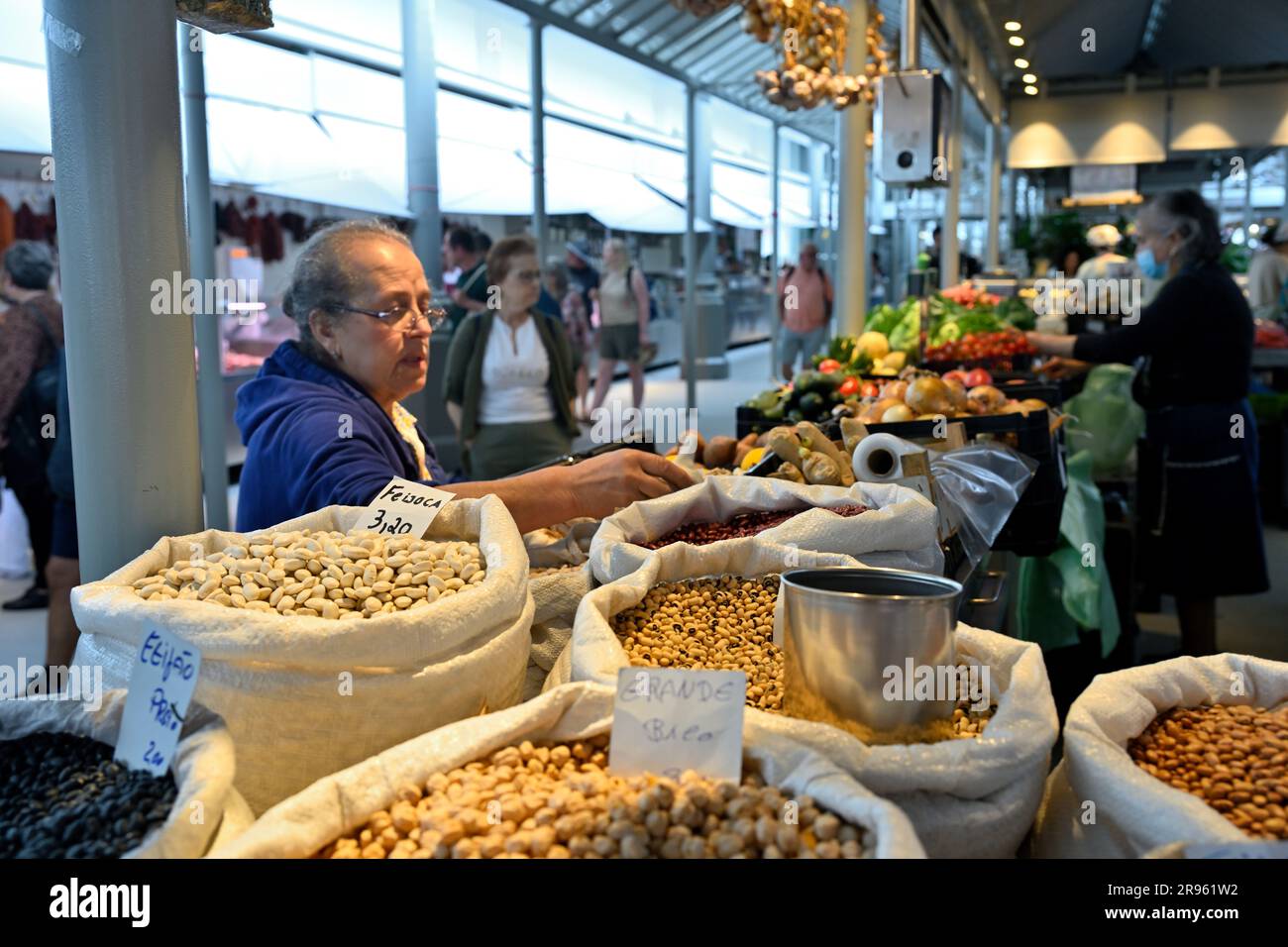 Vendeur vendant une variété de haricots secs avec des fruits et légumes sur le marché de Bolho avec sélection de clients, Porto, Portugal Banque D'Images