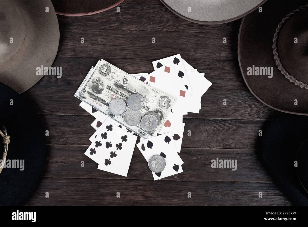 Vieux chapeaux de l'Ouest avec carte à jouer avec des papiers argent et pièces d'argent sur la table. Vue de dessus. Banque D'Images