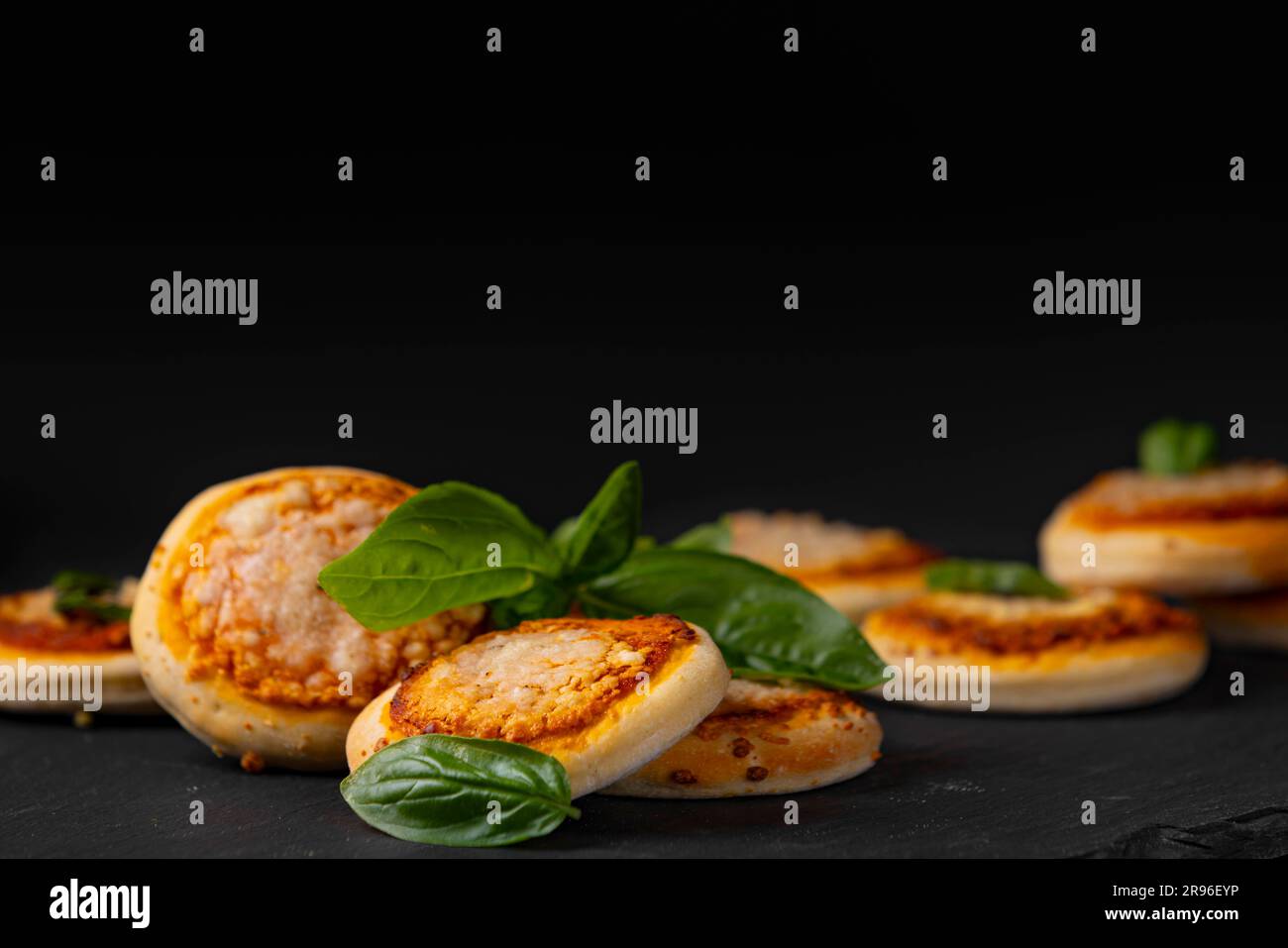 Mini Pizza Margherita, plusieurs sur plaque sombre, basilic, photographie alimentaire, fond sombre Banque D'Images