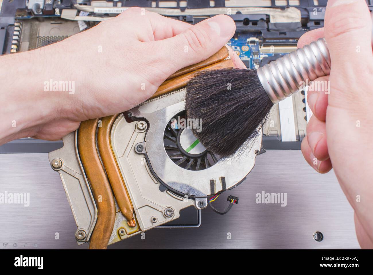Man nettoie le système de refroidissement du refroidisseur de l'ordinateur portable avec une brosse de la poussière, gros plan Banque D'Images