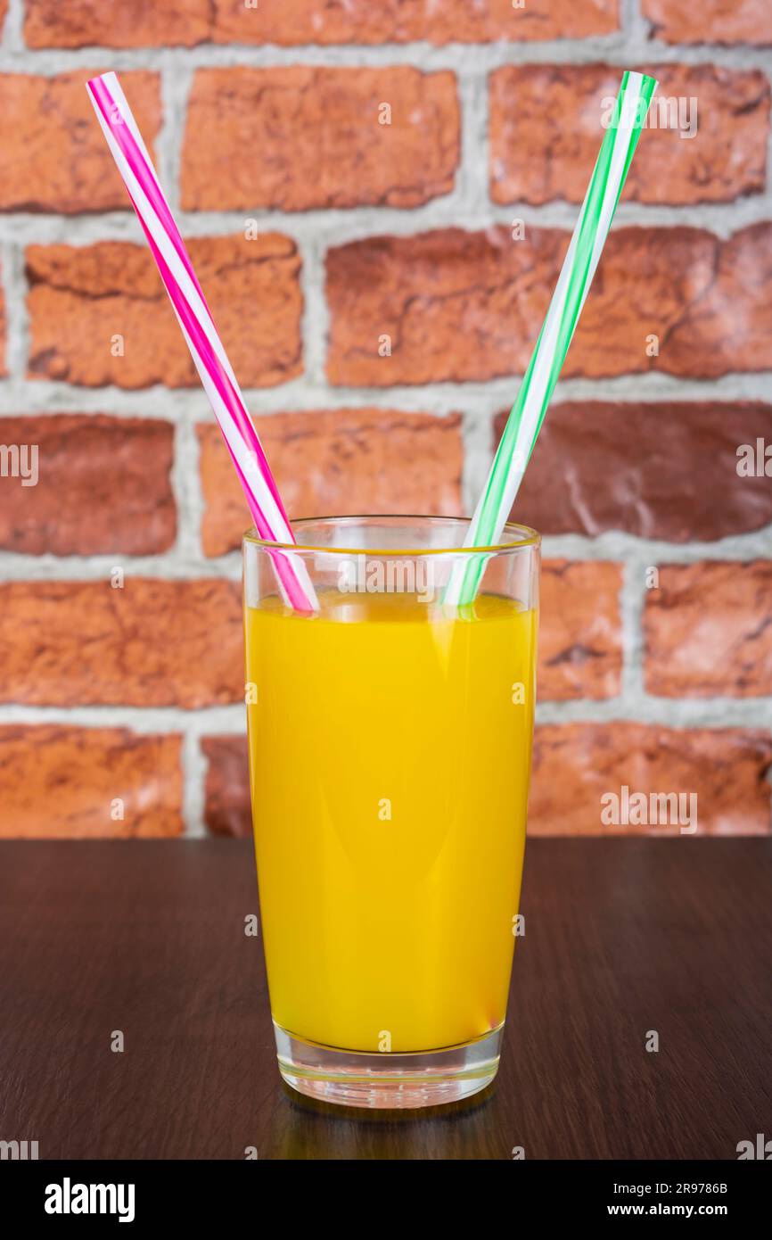 Jus d'orange dans un verre avec deux tubes Vitamins Health concept fond en bois et un mur de brique dans le fond Banque D'Images