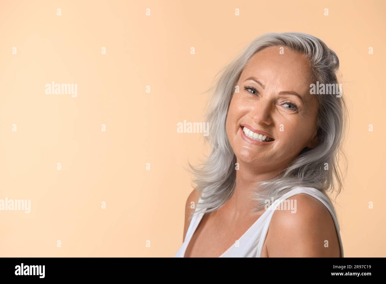 Portrait d'une femme souriante avec des cheveux de frêne sur fond beige. Espace pour le texte Banque D'Images