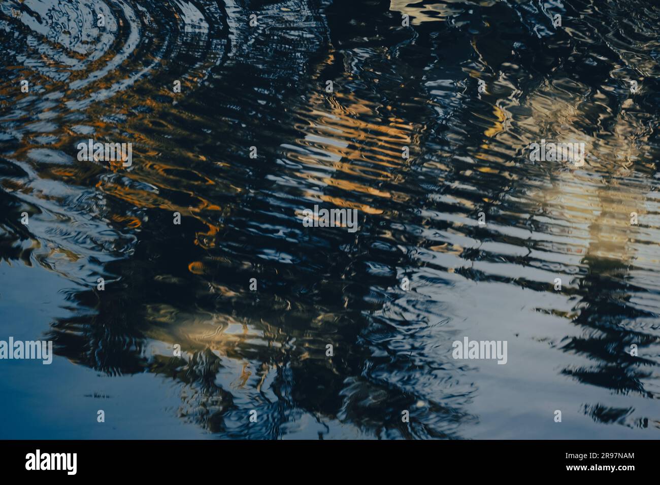 La scène tranquille de l'étang est astucieusement capturée par l'eau scintillante qui reflète à la fois le ciel et l'ombre des arbres. Banque D'Images