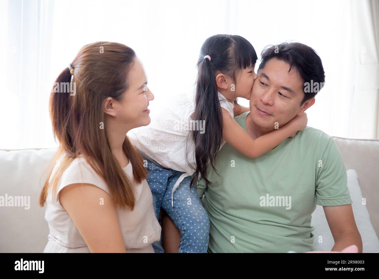 Bonne famille asiatique fille baiser cheek père et mère assis sur le canapé  dans le salon à la maison, papa et mère et enfant assis et se détendre avec  confortable Photo Stock -