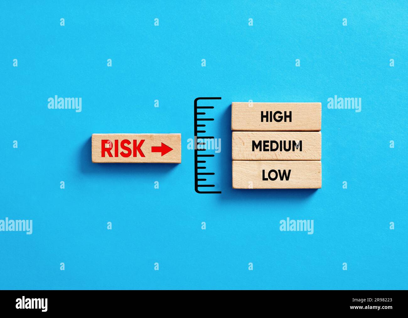 Prise de décision et analyse des risques. Gestion et évaluation des risques dans l'entreprise. Indicateur de niveau de risque avec blocs de bois sur fond bleu. Banque D'Images