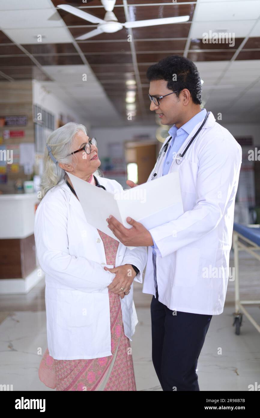 Femme médecin âgée et jeune homme médecin. Médecin lisant le rapport du patient sur la paperasse ou le document médical. Banque D'Images