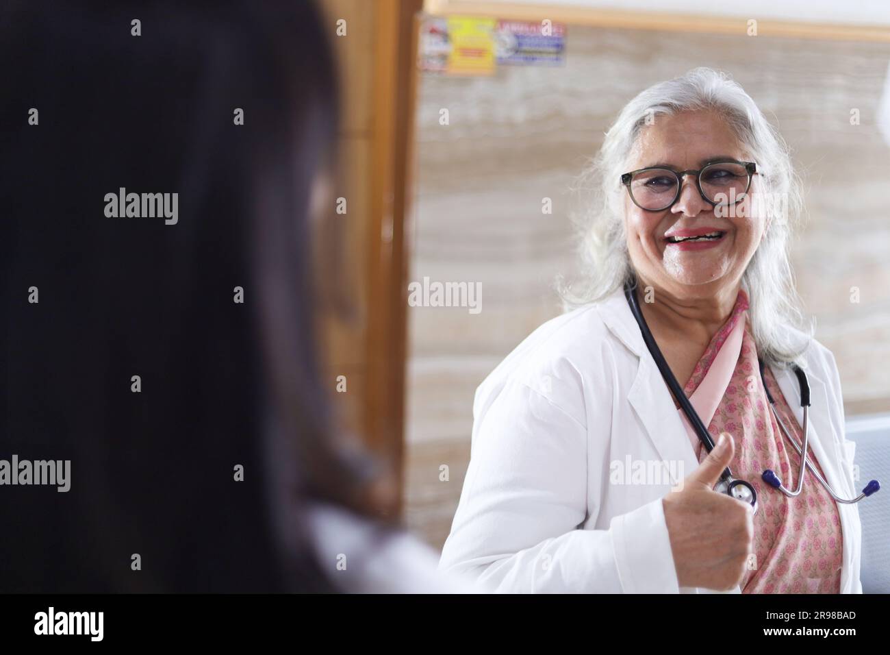 Médecin indien en discussion avec son assistant. Les médecins rient et parlent dans le couloir. Femme médecin âgée et jeune médecin. Médecin lisant le rapport du patient Banque D'Images