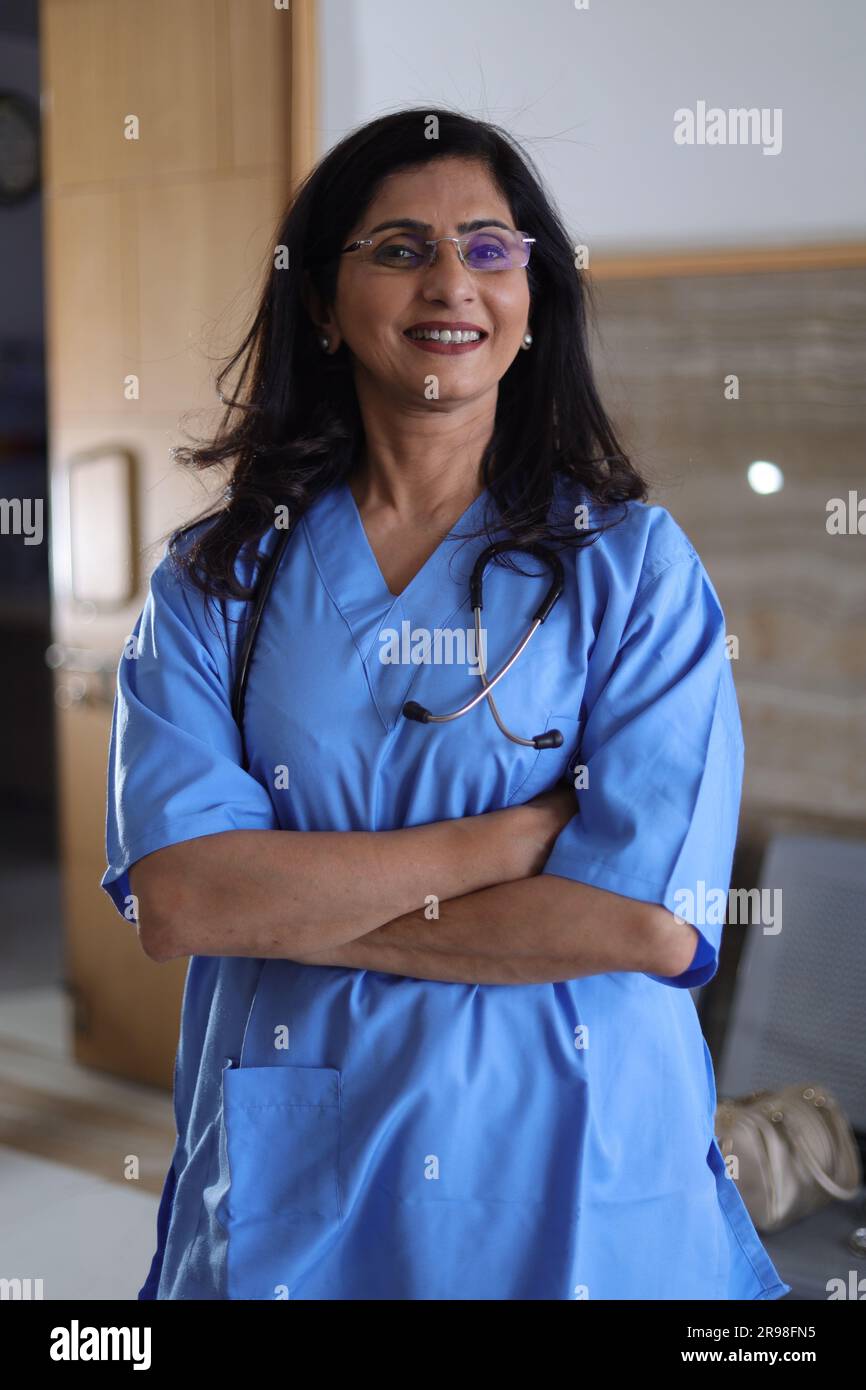 Portrait de femme médecin avec les bras croisés. Infirmière heureuse en uniforme bleu debout sur fond de couloir hospitalier. confiance Banque D'Images