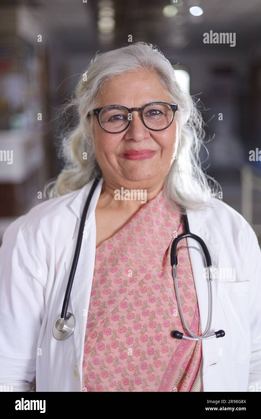 Portrait de femme médecin senior avec les bras croisés debout dans le couloir de l'hôpital. Heureux docteur indien blouse blanche de laboratoire Banque D'Images