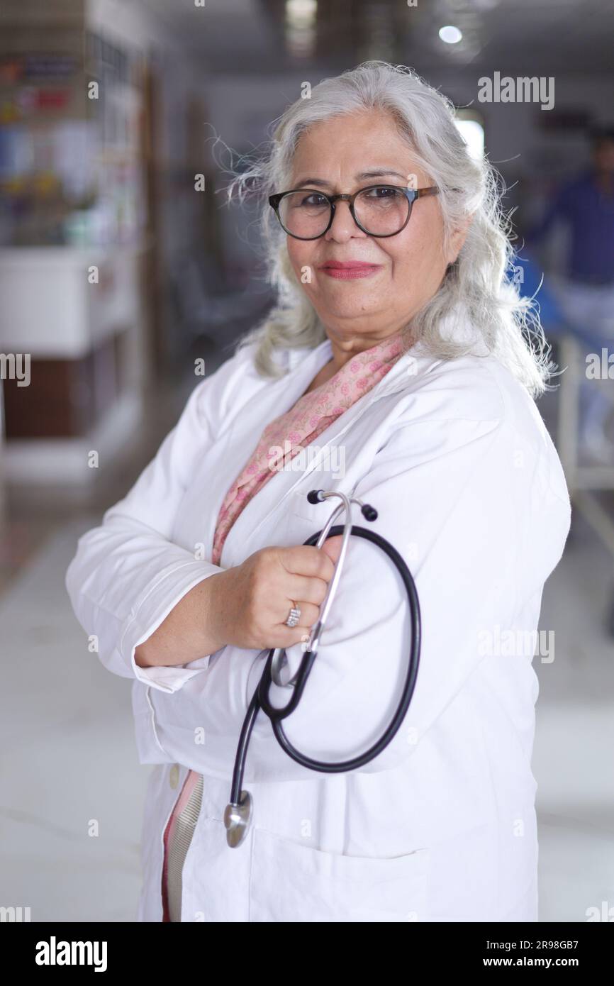 Portrait de femme médecin senior avec les bras croisés debout dans le couloir de l'hôpital. Heureux docteur indien blouse blanche de laboratoire Banque D'Images