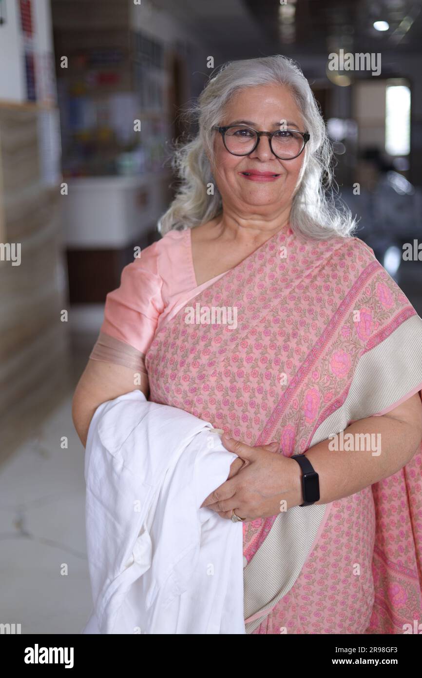 Portrait de femme médecin senior avec les bras croisés debout dans le couloir de l'hôpital. Heureux docteur indien blouse blanche de laboratoire Banque D'Images