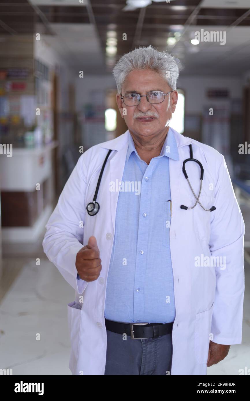 Portrait d'un médecin souriant en blouse de laboratoire montrant les pouces vers le haut. Heureux médecin senior en manteau blanc souriant sur fond de couloir d'hôpital. confiant. Banque D'Images