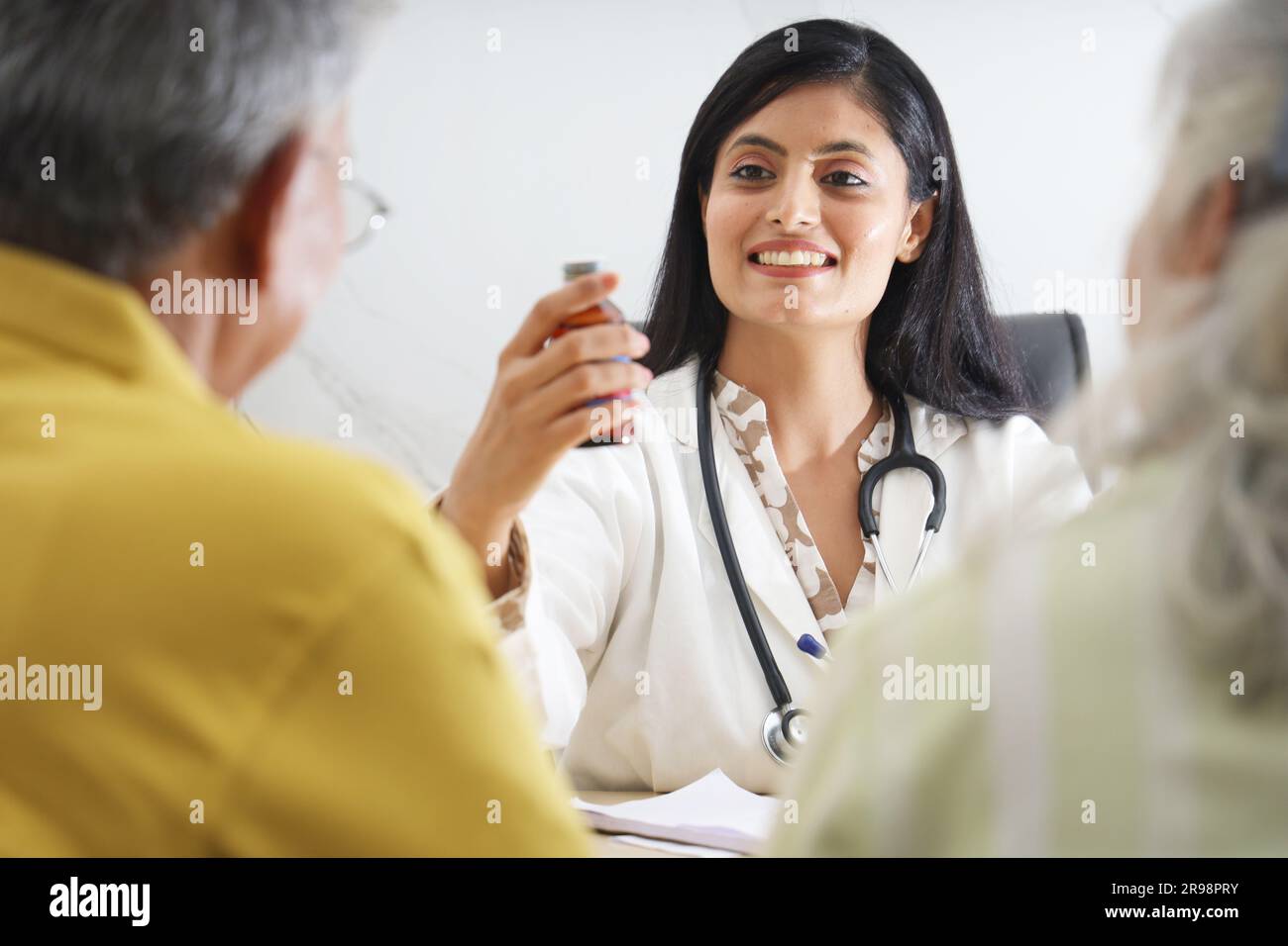 Attrayant jeune médecin indien assis avec un patient âgé dans le salon d'une maison de soins infirmiers. Un patient âgé ayant une conversation détaillée Banque D'Images