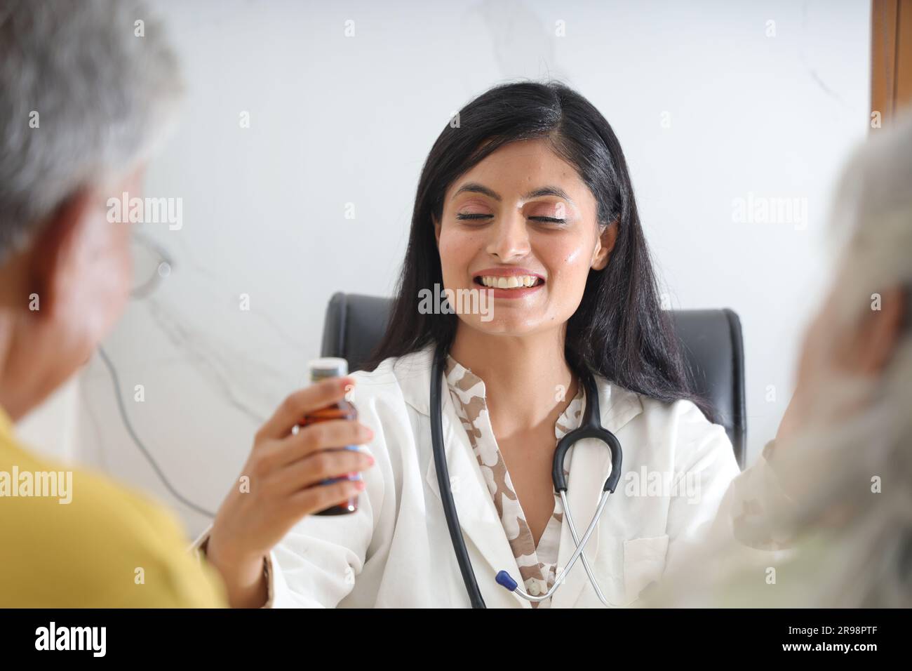 Attrayant jeune médecin indien assis avec un patient âgé dans le salon d'une maison de soins infirmiers. Un patient âgé ayant une conversation détaillée Banque D'Images