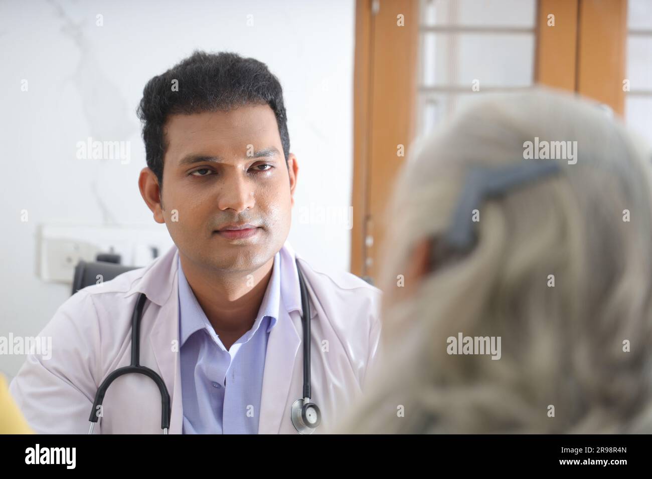 jeune médecin assis avec un patient âgé dans le salon d'une maison de retraite. Un patient âgé ayant une conversation détaillée. médecin de famille Banque D'Images