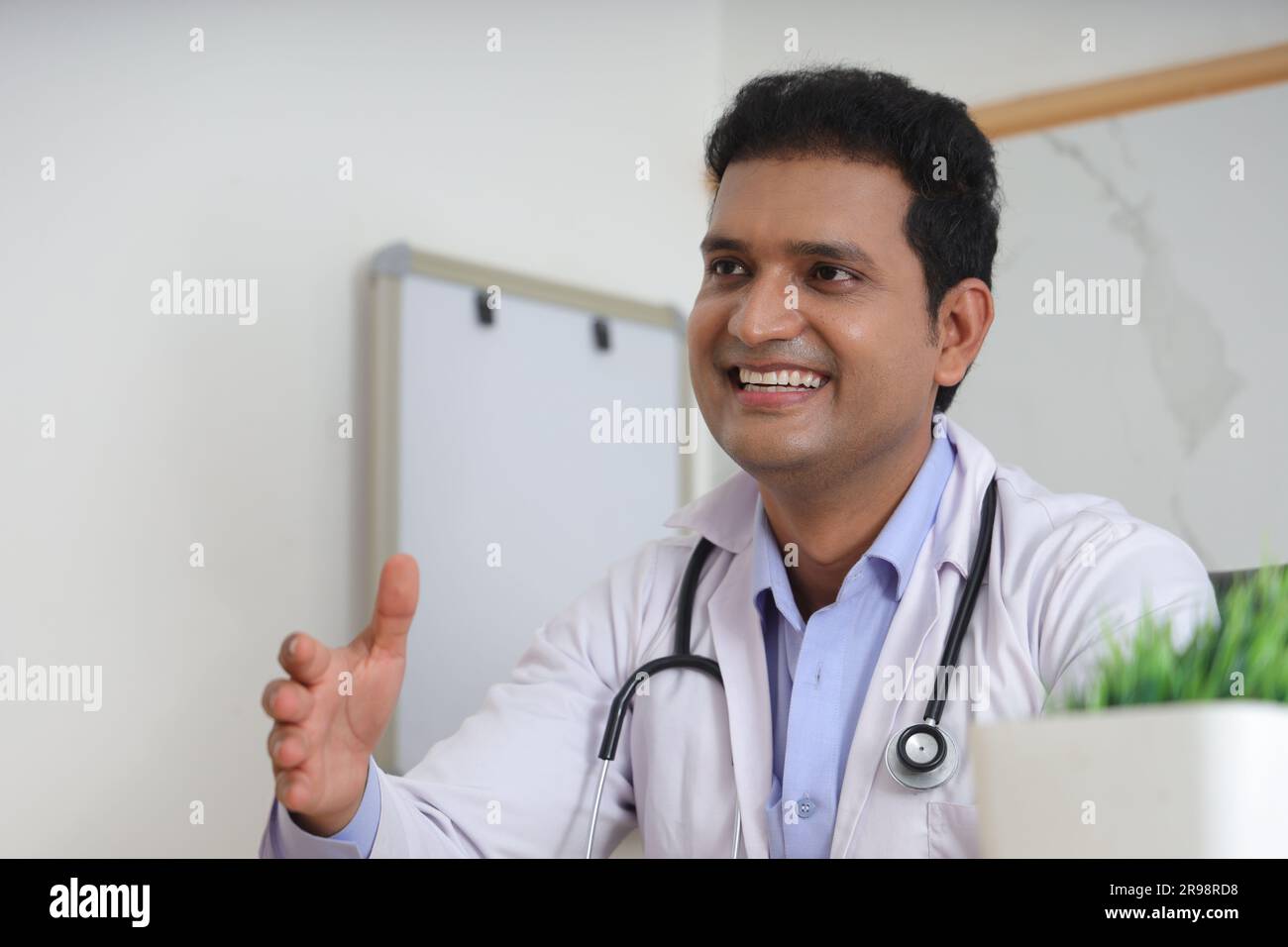 Jeune médecin indien assis avec le patient ayant une conversation détaillée. Heureux jeune docteur souriant. Concepts de services de consultation. Stéthoscope. Banque D'Images