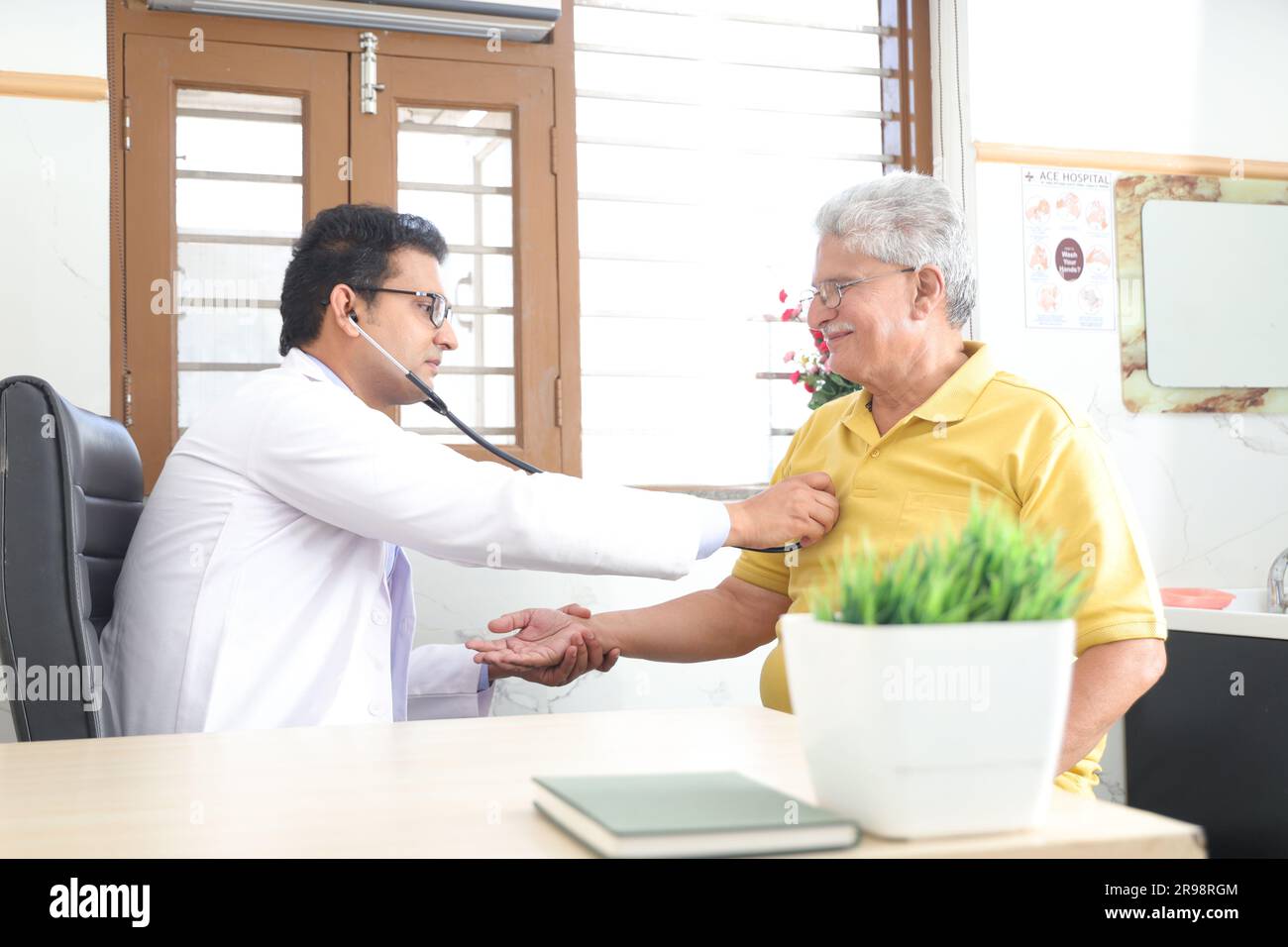 jeune médecin assis avec le patient âgé dans le cabinet du médecin. patient âgé ayant une conversation détaillée avec le médecin féminin, vérifiant la fréquence cardiaque. Banque D'Images