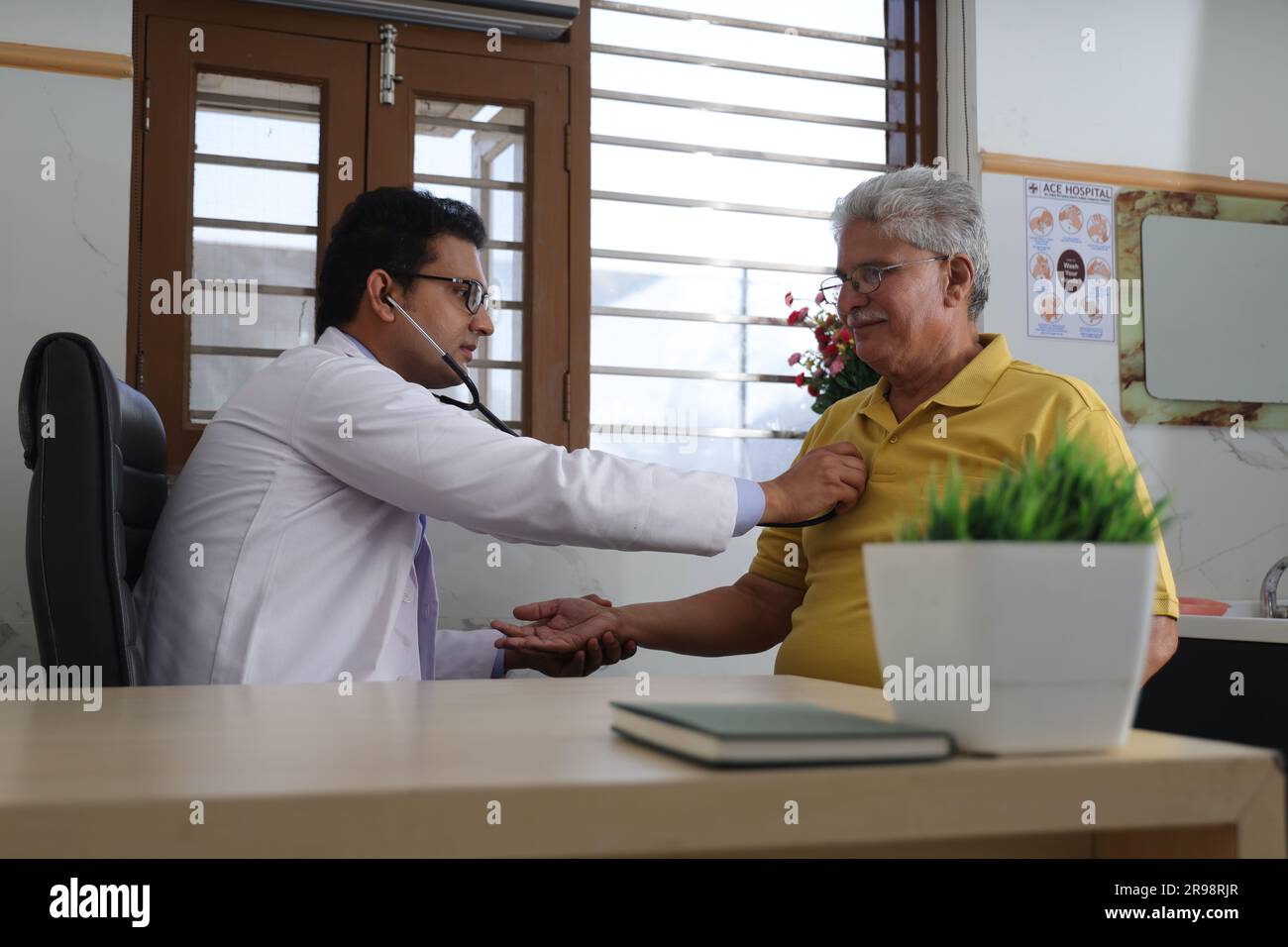 jeune médecin assis avec le patient âgé dans le cabinet du médecin. patient âgé ayant une conversation détaillée avec le médecin féminin, vérifiant la fréquence cardiaque. Banque D'Images