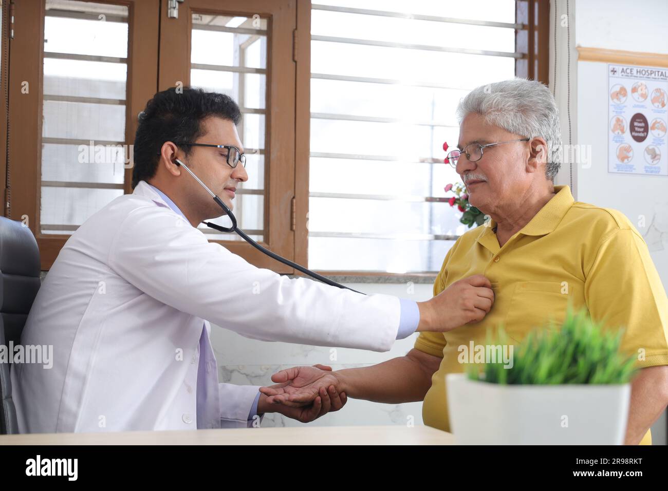 jeune médecin assis avec le patient âgé dans le cabinet du médecin. patient âgé ayant une conversation détaillée avec le médecin féminin, vérifiant la fréquence cardiaque. Banque D'Images