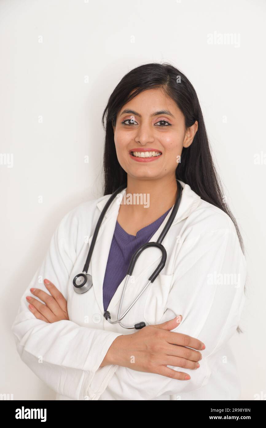 Portrait d'indienne souriante médecin senior en blouse de laboratoire avec les bras croisés sur fond bleu. Heureux docteur indien en manteau blanc souriant sur ho Banque D'Images