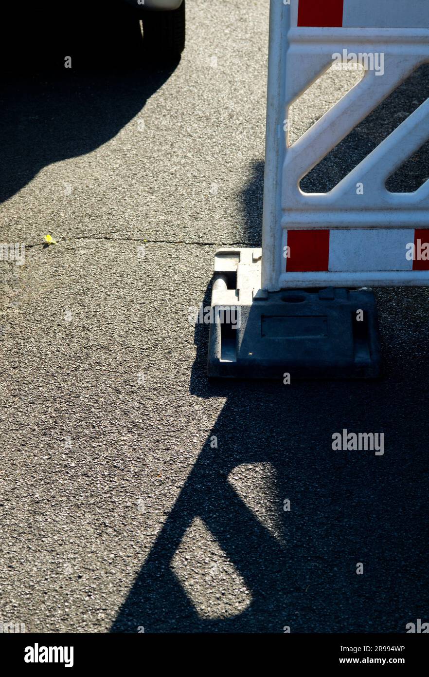 détail d'un feu à éclats rouge et blanc sur la route avec un modèle de lumières et d'ombres sur l'asphalte Banque D'Images