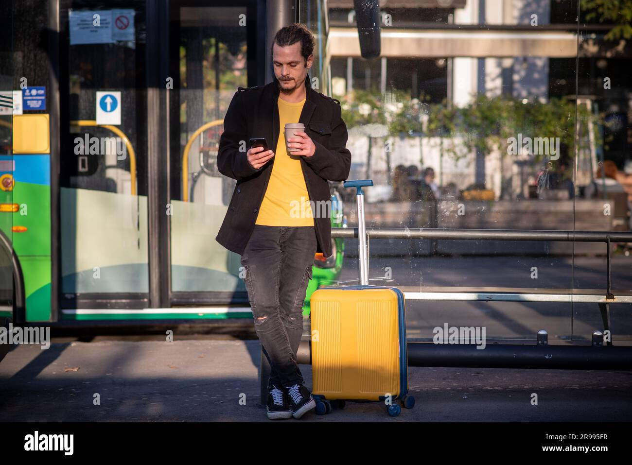 Touriste avec une valise à roulettes en attente d'un bus Banque D'Images