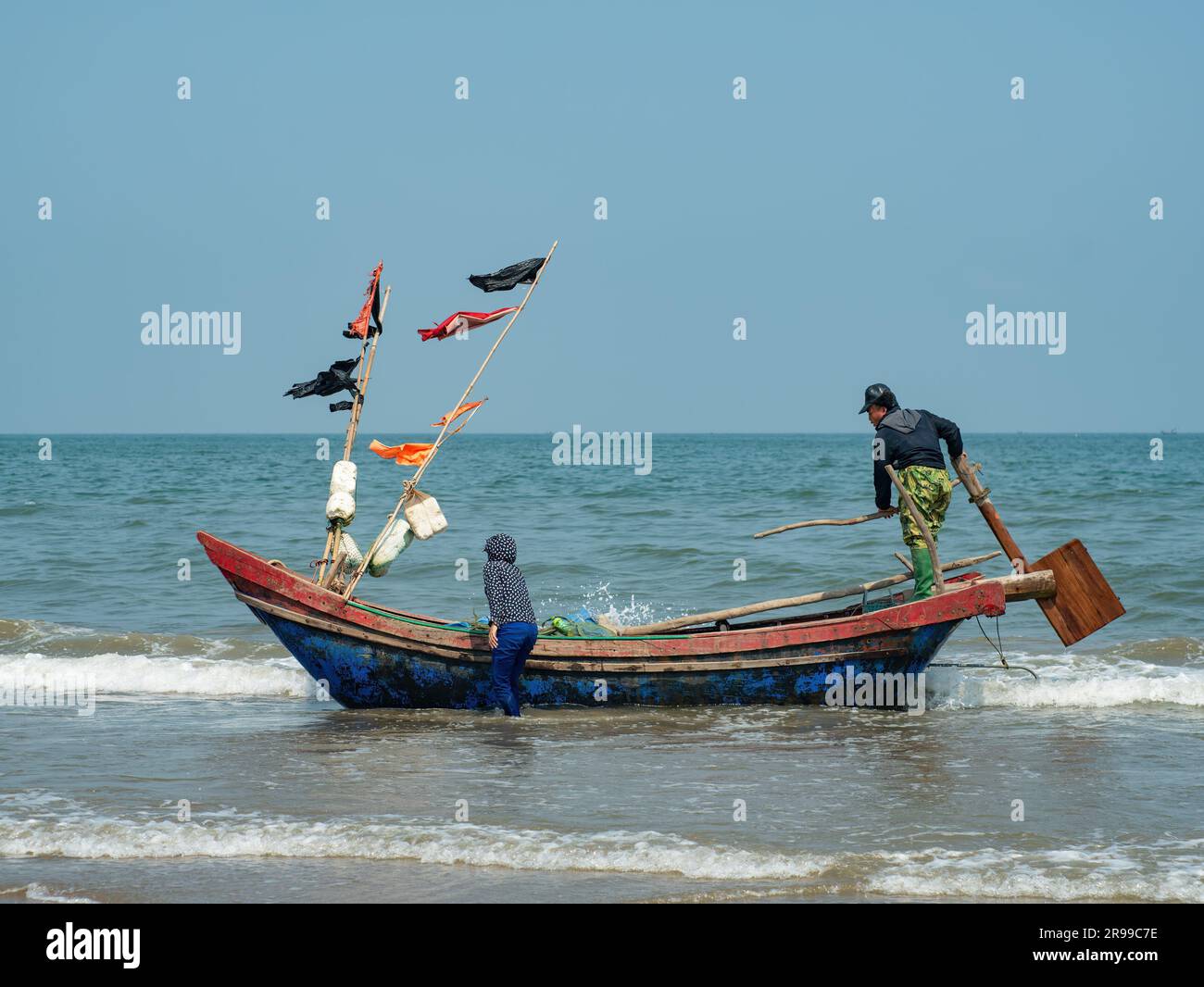 Couple vietnamien se préparant à transporter leur bateau de pêche sur la plage de Sam son, province de Thanh Hoa du Vietnam. Banque D'Images