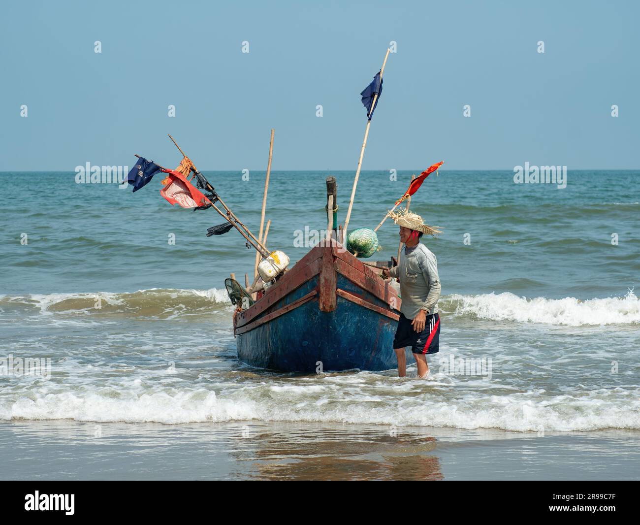 Pêcheur vietnamien se préparant à transporter son bateau de pêche sur la plage de Sam son, province de Thanh Hoa du Vietnam. Banque D'Images