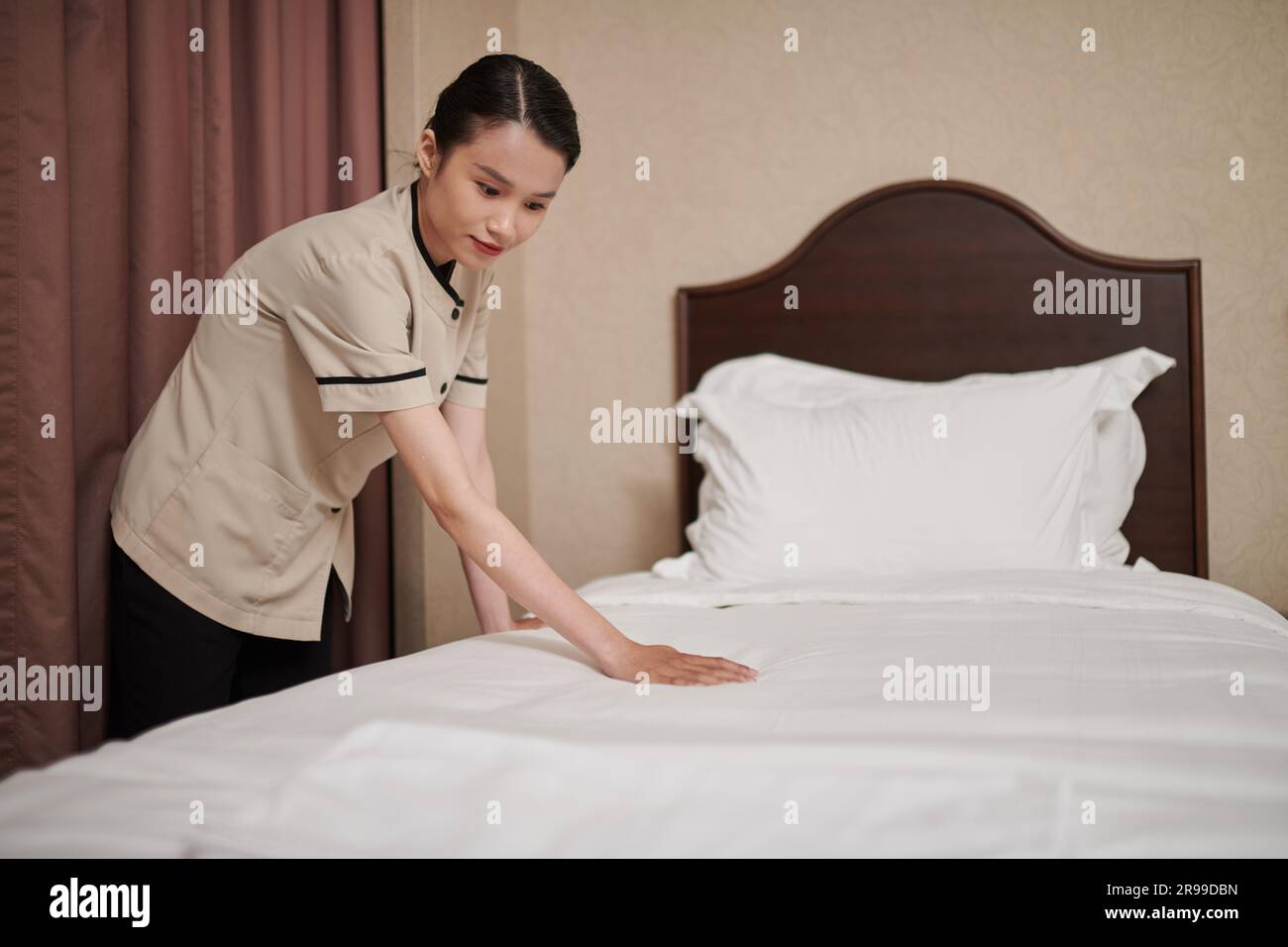 La femme de ménage de l'hôtel change le linge et fait le lit pour les nouveaux clients Banque D'Images