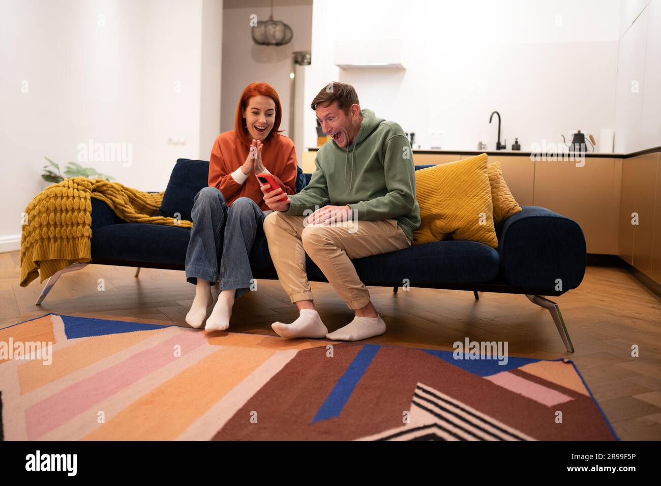 Joyeux jeune couple joyeux du millénaire heureux de regarder l'écran du téléphone crier avec joie Banque D'Images